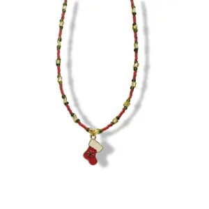 Κολιέ μπότα του Άγιου Βασίλη κόκκινη με χρυσή χιονονιφάδα και πάνω πάνω άσπρο για χιόνι. Οι χάντρες είναι περασμένες με σειρά: 5 κόκκινες μικρές, μια πιο μεγάλη πράσινη, μια ακόμα πιο μεγάλη και μακρόστενη χρυσή, πάλι πράσινη, 5 κόκκινες και το μοτίβο επαναλαμβάνεται.